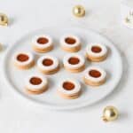 Marillenringe cookies with golden dough and tart apricot jam, dusted in dark icing sugar, arranged with holiday decorations.