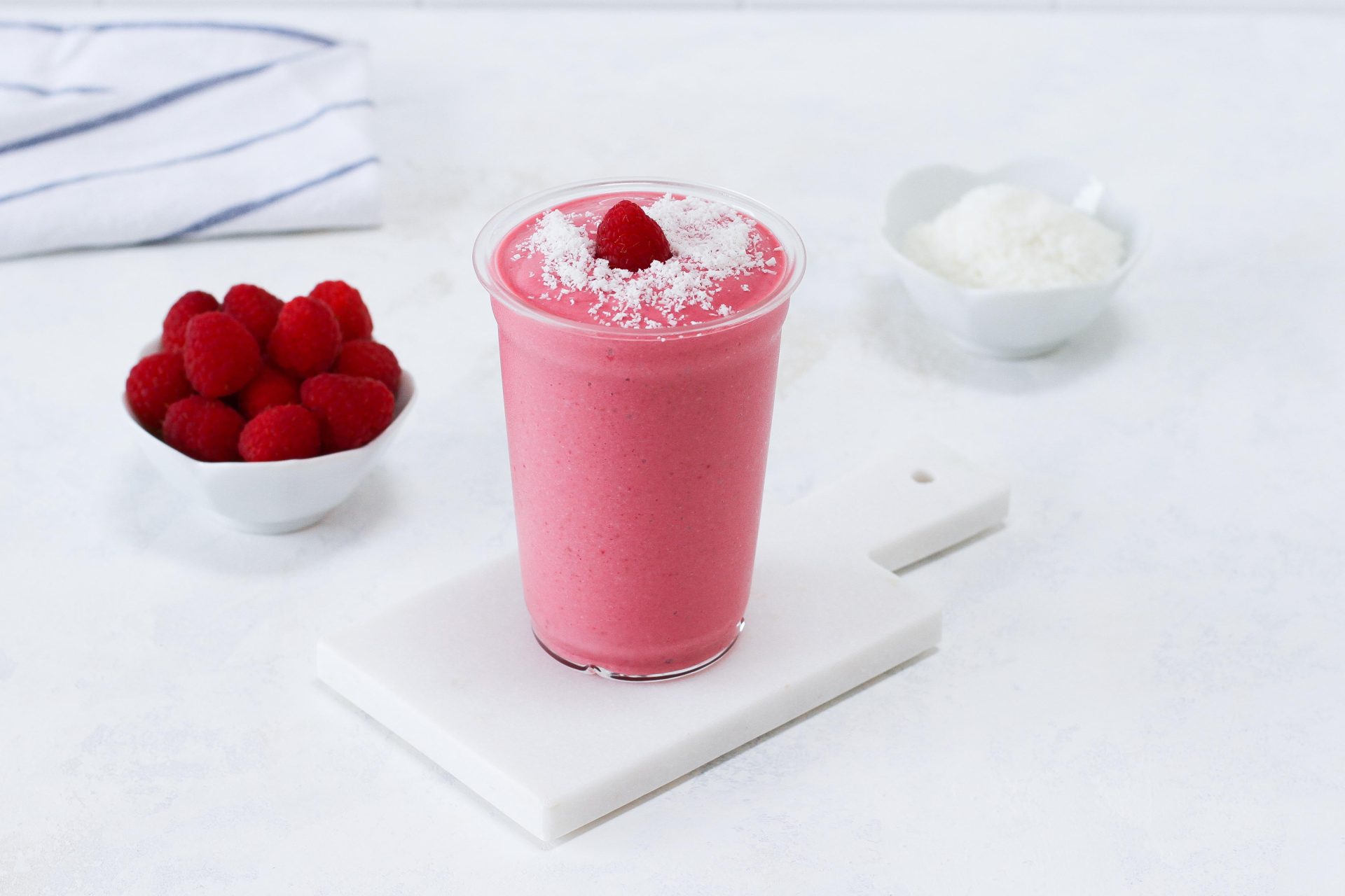 Cup with raspberry coconut smoothie and a raspberry as decoration